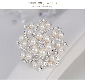 Vue macro d'une broche florale argentée avec perles blanches et strass étincelants