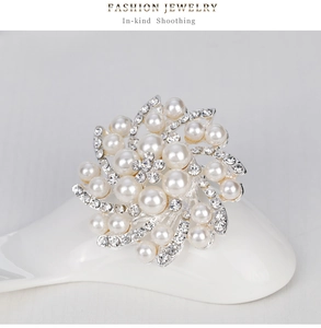 Détail d'une broche fleurie argentée avec perles blanches élégantes et strass brillants