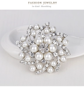 Vue détaillée de la broche fleur argentée avec perles blanches et strass étincelants