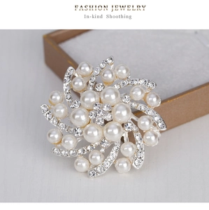 Détail de la broche florale en spirale avec perles blanches et strass scintillants