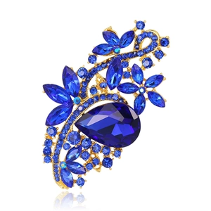 Squisita spilla floreale dorata con un grande cristallo blu a pera e strass lucidi