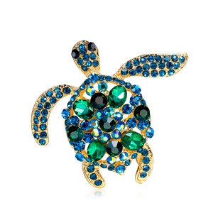 Elegant gold-tone sea turtle brooch featuring blue and green rhinestones on white background