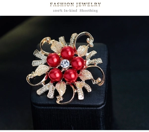 Detailed view of vintage gold hollow flower brooch with red pearls and central crystal