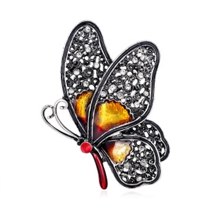 Detailed macro view of butterfly brooch featuring yellow enamel and red crystal stone