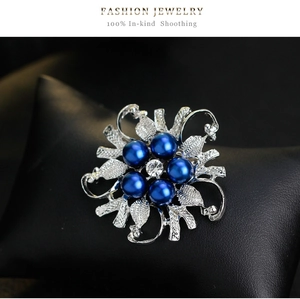 Detail view of a vintage silver flower brooch with deep blue pearls and a center crystal