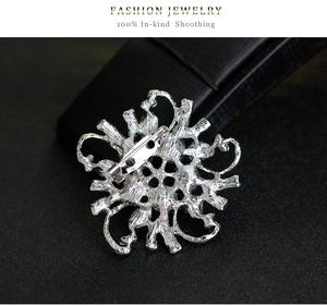 Detailed back view of a silver flower brooch showing the metal pin fastener on black leather