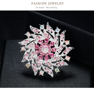 Vue macro d'une broche fleur argentée avec strass roses et tissage métallique évidé