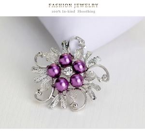 Macro shot of silver alloy flower brooch with purple pearls and central crystal detail