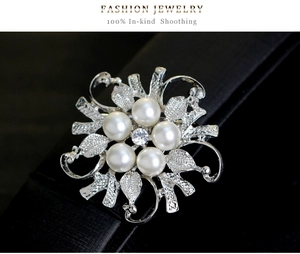 Close-up of floral silver brooch with white pearls and sparkling rhinestone center