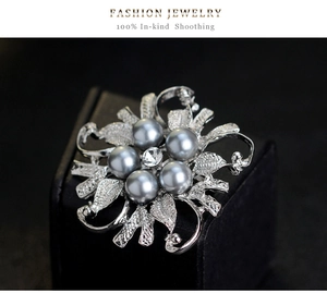Macro detail of a silver flower brooch with grey pearls and clear rhinestones