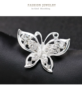 Detailed close-up of a silver butterfly brooch with sparkling crystals on black leather