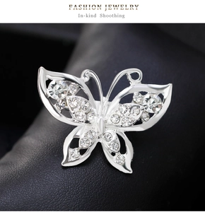 Detail of silver butterfly brooch with sparkling crystals on black leather background
