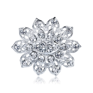 Broche fleur argentée évidée avec strass étincelants sur fond blanc avec reflet