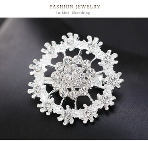 Macro shot of silver snowflake brooch with sparkling rhinestones on black fabric