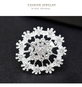 Macro shot of a silver snowflake brooch with sparkling zircons on black fabric background