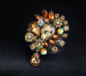 Macro shot of vintage crystal flower brooch with amber gems on gold metal base