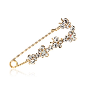 Macro detail of gold-plated safety pin brooch with sparkling white cubic zirconia stones