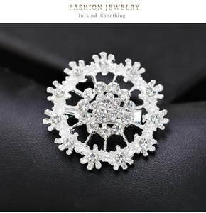 Detailed view of a silver-plated snowflake brooch with sparkling rhinestones on black leather