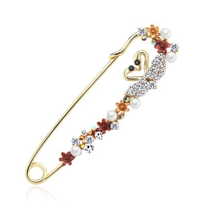 Close-up of golden swan brooch with white rhinestones, pearls and resin flowers
