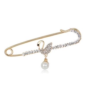 Macro detail of golden swan brooch with white crystals and a hanging pearl drop charm