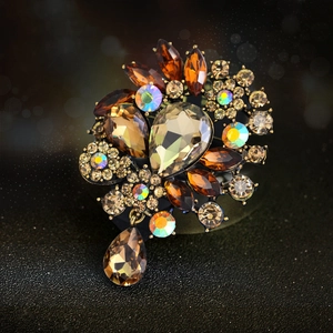 Vintage floral brooch with amber crystals and teardrop pendant on dark background