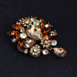 Vintage floral brooch with amber crystals and teardrop pendant on black backdrop