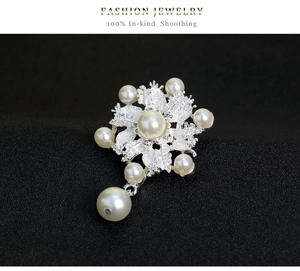Vista detallada de broche de flor con perlas blancas y brillantes de imitación en pétalos