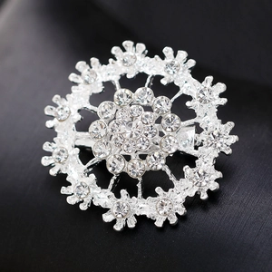 Silver-plated snowflake brooch with sparkling rhinestones on textured black background