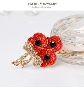 Dettaglio della spilla a fiore di papavero rosso con fiocco di cristallo e strass su sfondo bianco