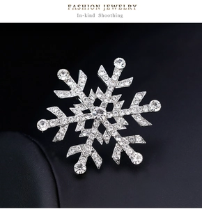 Vue macro de la broche flocon de neige argentée avec strass sur fond de cuir noir texturé