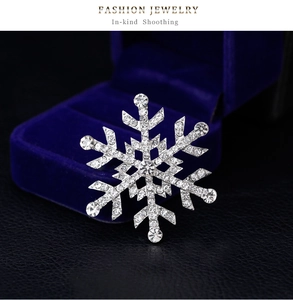 Détail d'une broche flocon de neige argentée avec cristaux sur boîte à bijoux en velours