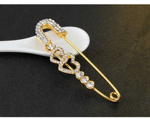 Detailopname van de gouden veiligheidsspeld-broche met hartjes en fonkelende strasstenen