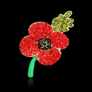 Detailed macro of red crystal poppy brooch with green enamel stem and gold frame