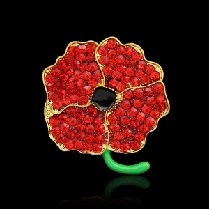 Macro shot of red rhinestone poppy brooch with black enamel center and gold stem detailing