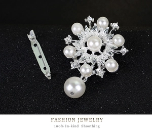 Detalle de broche de flor plateado con perlas blancas y cristales brillantes