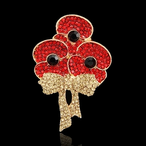Macro detail of poppy brooch with red rhinestones and gold pavé crystal bow design