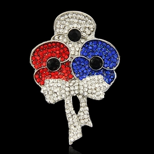 Detailed view of crystal poppy brooch with red enamel petals and sparkling silver bow