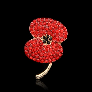 Macro shot of a sparkling red poppy brooch with paved crystals and polished gold stem