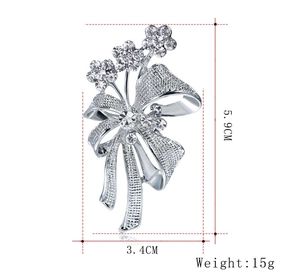 Détails de la broche nœud argentée avec strass indiquant les dimensions 5,9 cm sur 3,4 cm