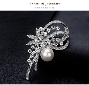 Détail macro d'une broche narcisse argentée avec grande perle et strass scintillants