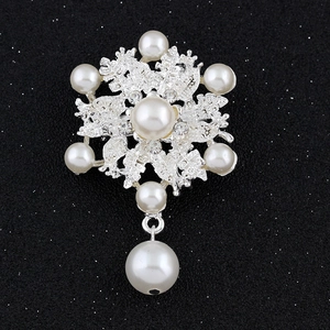 Elegante broche de copo de nieve plateado con perlas y cristales sobre fondo negro mate