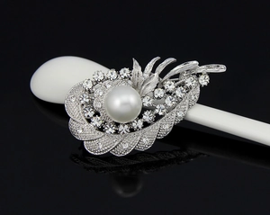 Macro detail of a vintage feather brooch with sparkling rhinestones and a white pearl
