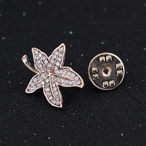 Macro detail of rose gold maple leaf brooch featuring white crystal pave and butterfly clutch