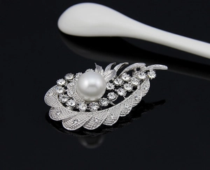 Macro detail of silver feather brooch with white pearl and sparkling rhinestones