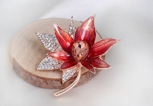 Detailed close-up of maple leaf brooch with red enamel and sparkling white rhinestones