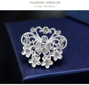 Macro detail of silver floral rhinestone brooch with intricate hollow design on jewelry box