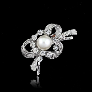 Elegant silver bow brooch with sparkling crystals and a white pearl on black background