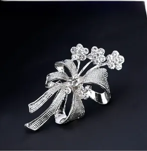 Détail de la broche nœud argenté ajouré avec strass brillants et motifs floraux fins