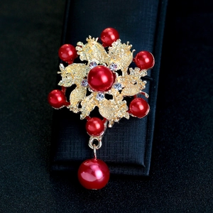 Elegante broche de flor dorada con perlas rojas y cristales en caja de joyas