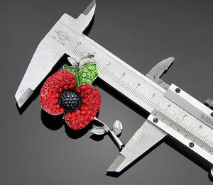 Detailed measurement of red crystal poppy brooch showing 3.5cm width with a caliper